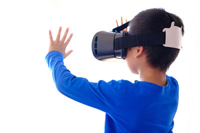 Boy holding camera while standing against wall