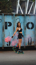 Full length portrait of woman holding flare wearing inline skates