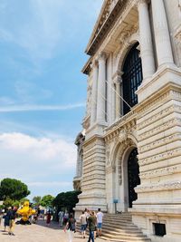 People outside historic building against sky