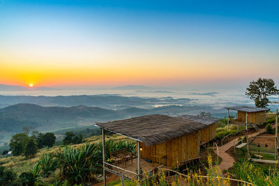 Scenic view of landscape and houses against sky during sunset