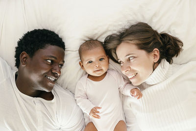 Parents with daughter lying on bed at home