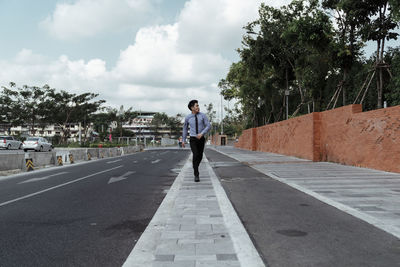 Rear view of man on road against sky in city