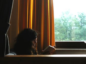 Rear view of woman looking through window