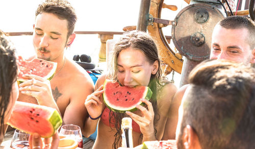 Friends eating watermelon slices on boat