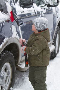 Boy cleaning snowy car