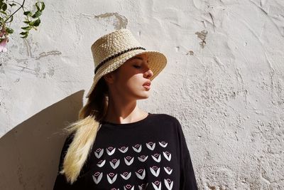 Portrait of young woman standing against wall