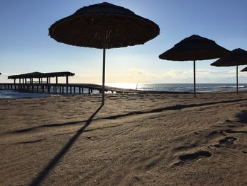 Parasols at sandy beach against sky