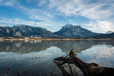 Scenic view of lake by snowcapped mountains against sky