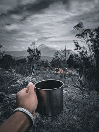 Midsection of person holding drink against sky