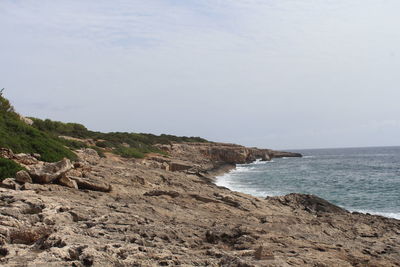 Scenic view of rocky beach against sky