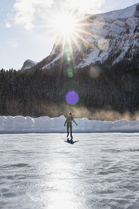 Young woman skating on frozen lake louise during cold winter day