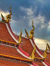 Low angle view of sculptures on roof of building against sky