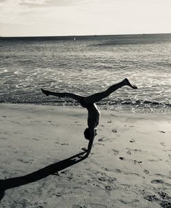 Girl practicing handstand at beach