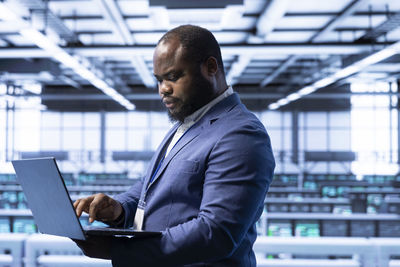 Young man using laptop while standing in office