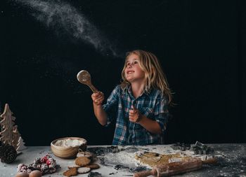 Portrait of girl holding wooden spoon baking christmas cookies