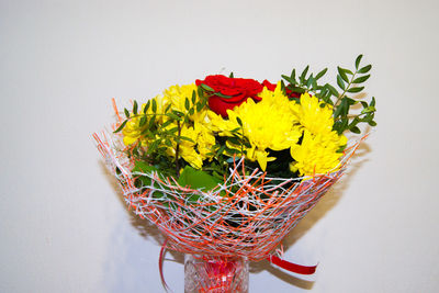 Close-up of multi colored flowers on table against wall