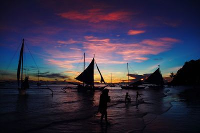 Silhouette sailboats on sea against sky during sunset