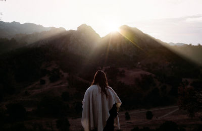 Rear view of woman looking at mountains against sky