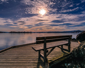 Pier over lake against sky during sunset