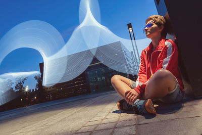 Portrait of young woman sitting outdoor on a ground on a long exposure, freeze light concept