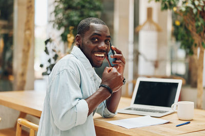 Side view of man using laptop while sitting on table