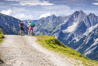 People riding bicycle on mountain against sky