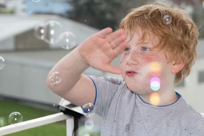 Close-up of boy gesturing with bubbles in mid-air