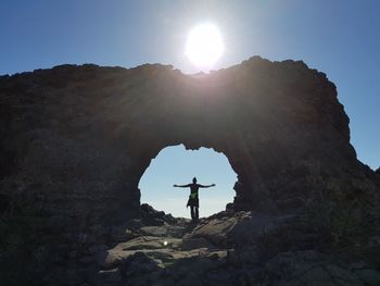 Man standing on rock against sky