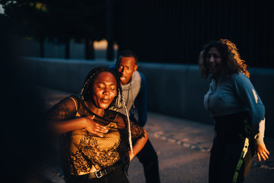 Teenage girl dancing with friends at skateboard park