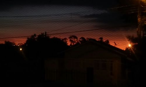 Power lines against sky at sunset