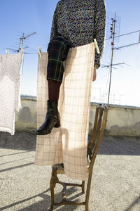 Low section of woman standing by clothesline on building terrace