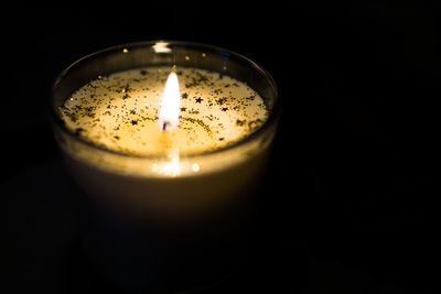 Close-up of lit tea light candle against black background