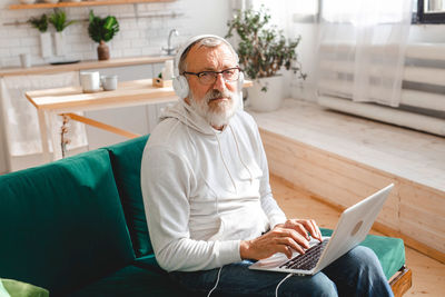 Portrait of senior man using mobile phone while sitting on sofa at home