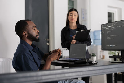 Side view of man using laptop at office