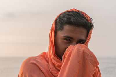 Portrait of man wearing scarf against sea at beach