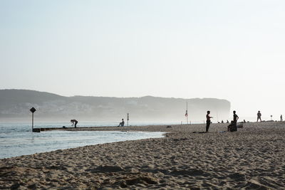 People on beach against clear sky