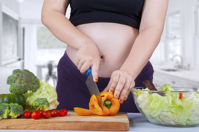 Midsection of woman cutting vegetables at home