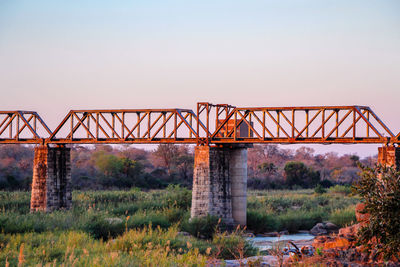 Old bridge over field against clear sky