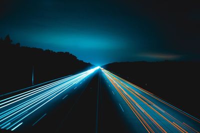 Light trails on road against sky at night