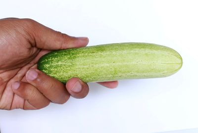 Close-up of hand holding watermelon over white background
