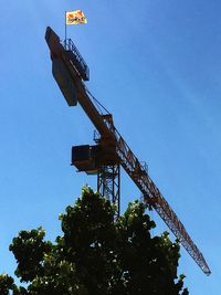 Low angle view of crane against clear blue sky