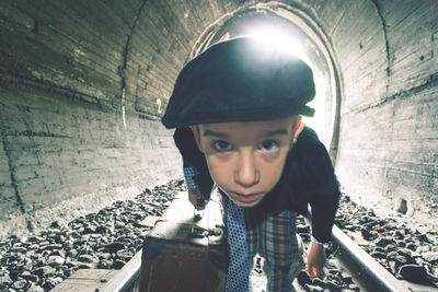 Portrait of boy with luggage in tunnel