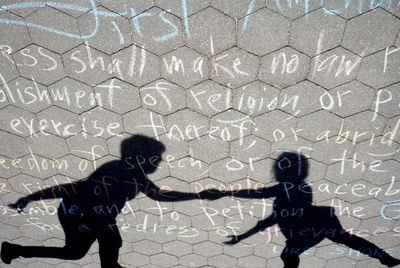 Shadow of friends on text over footpath