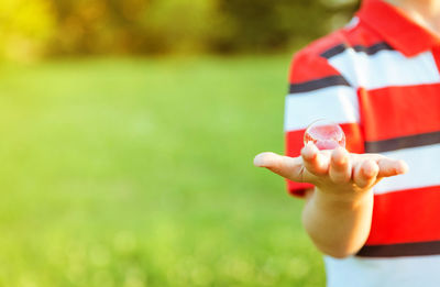 Close-up of hand holding red ball on field