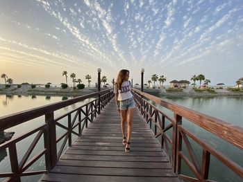 Woman standing on pier over sea against sky