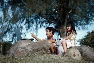 Women sitting on rock against trees