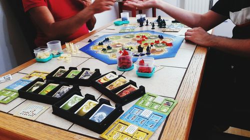 Midsection of friends playing board game on table at home