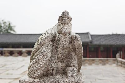 Statue of angel against building against clear sky