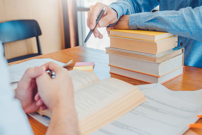 Midsection of man reading book on table