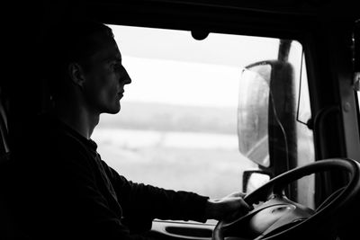 Side view of man sitting in car